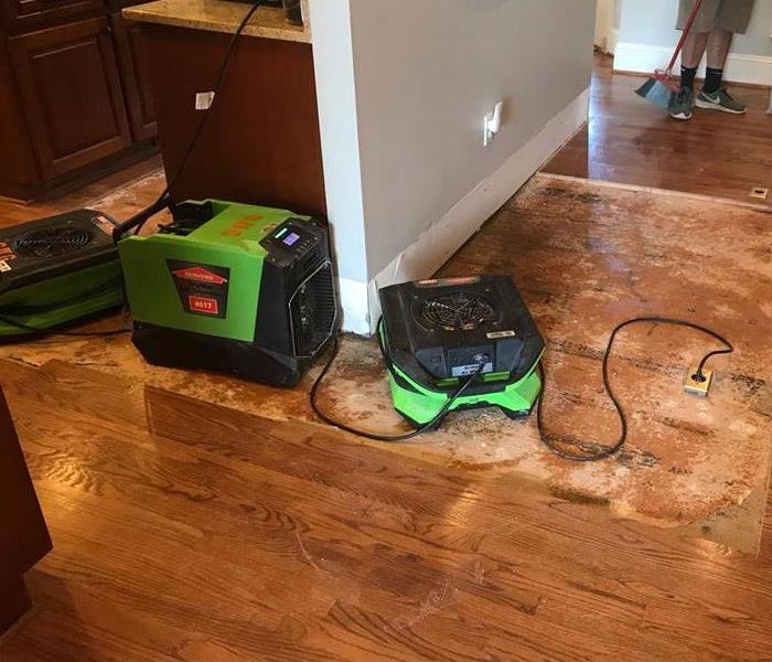 Photo of air movers on removed flooring drying subfloor